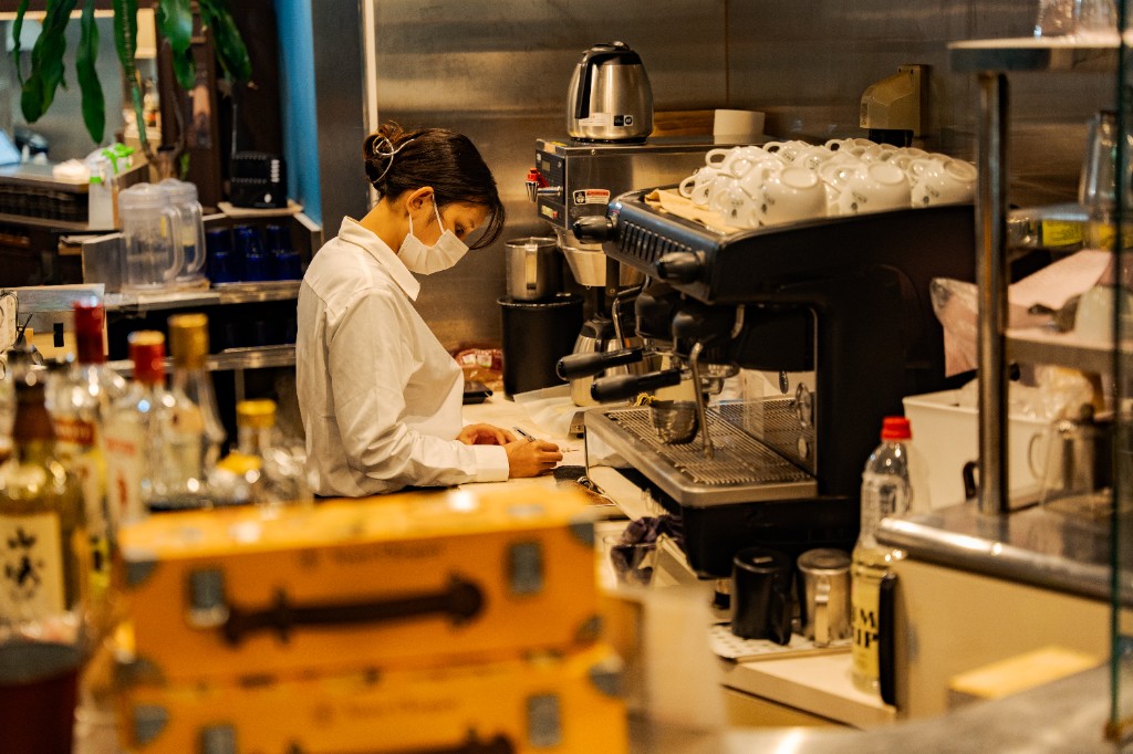 カウンターで接客・記入業務を行うスタッフ。エスプレッソマシンや店内の様子