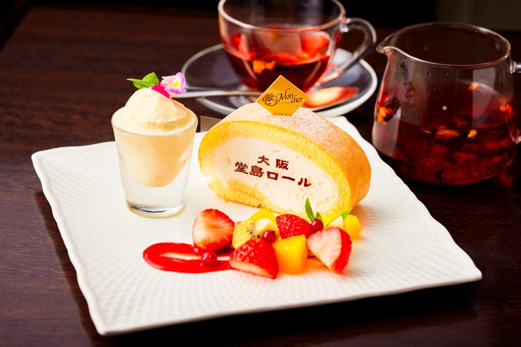 堂島ロールのスライス。フルーツとアイス、フレーバー紅茶とともに白い皿に盛り付けられた一皿