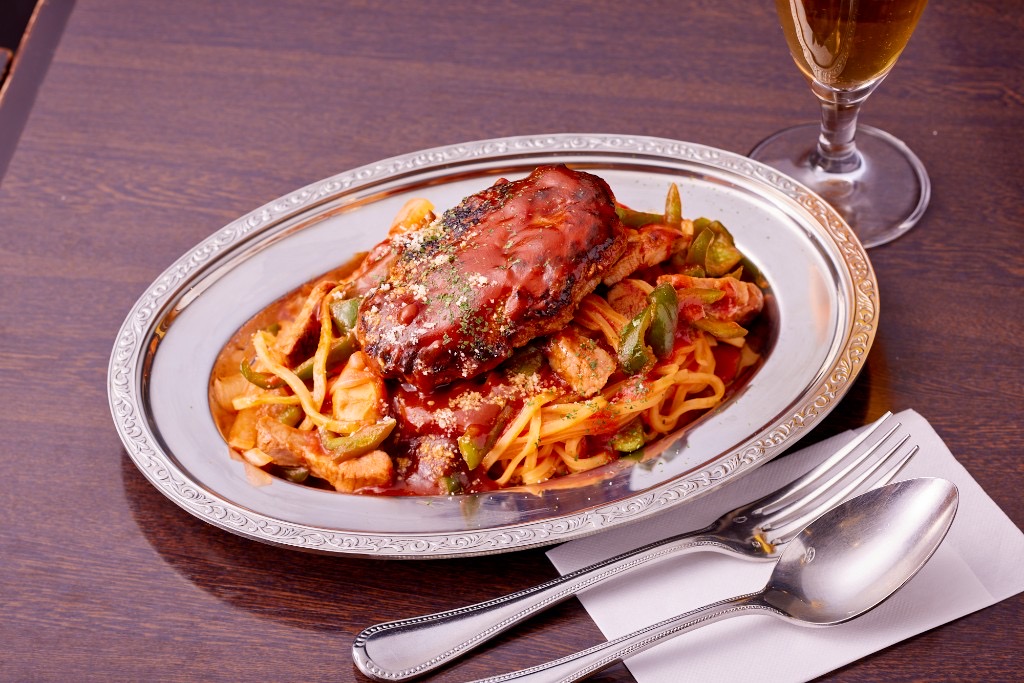 名物ナポリタンにハンバーグをのせた一皿。銀の皿にケチャップソースとパルメザン